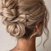 A woman's hair is styled in an elegant updo using brown hair and clear bobby pins.