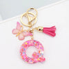 Alphabet letter acrylic keychain shaped like a pink butterfly with a pink tassel