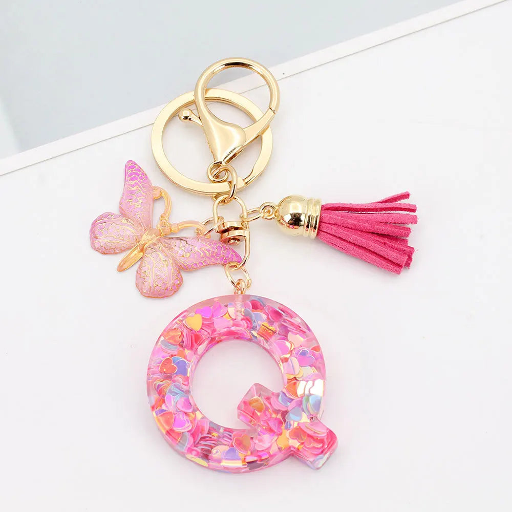 Alphabet letter acrylic keychain shaped like a pink butterfly with a pink tassel