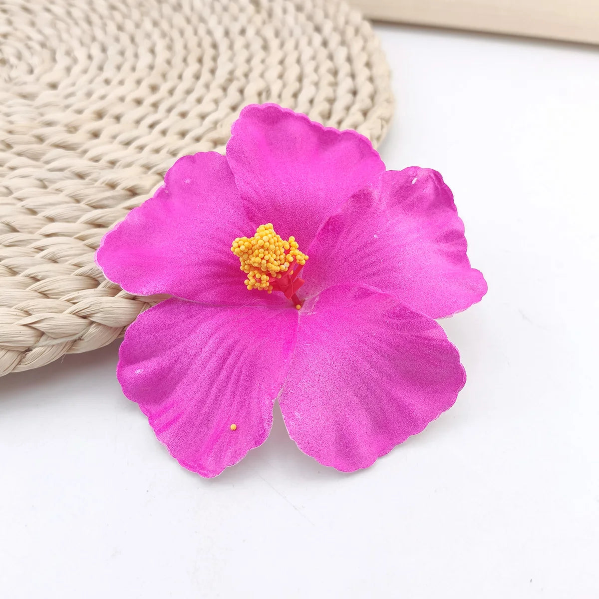 A vibrant magenta hibiscus flower resting on a woven natural fiber background.