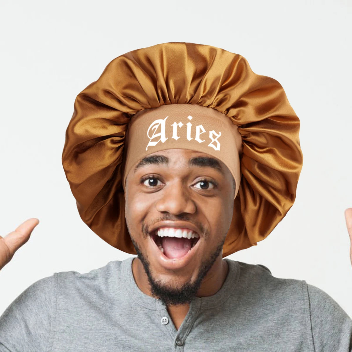A man wearing a satin sleep bonnet with a wrap band, featuring the word Aries embroidered on the fabric.