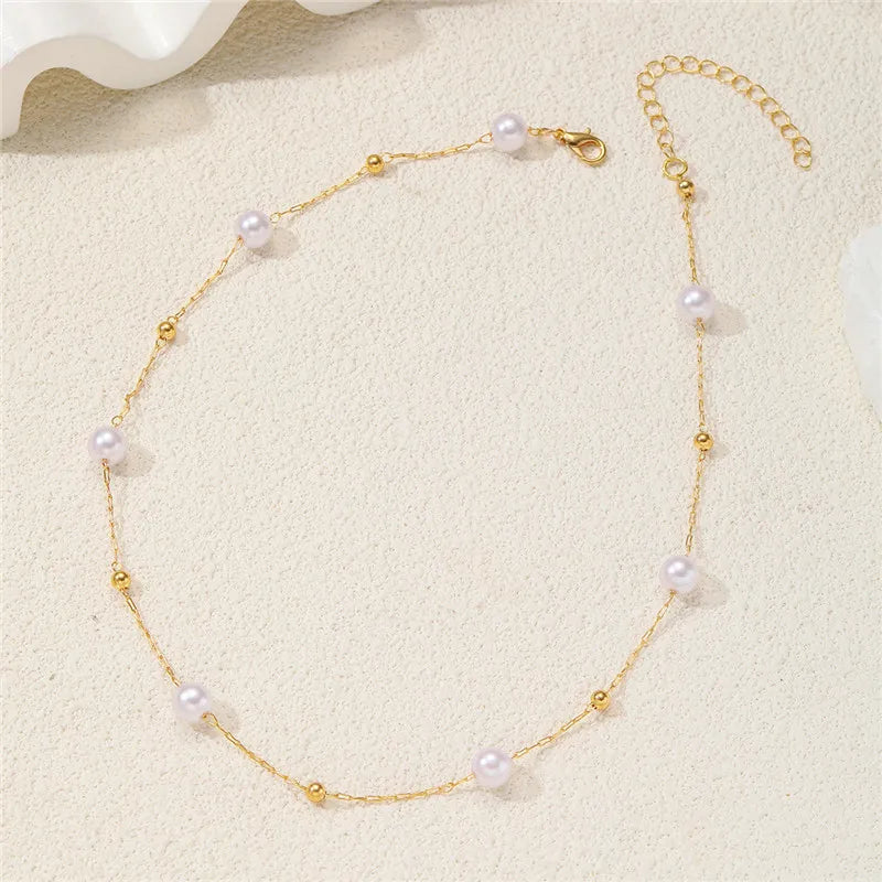 Un délicat collier en or avec de petites perles blanches rondes.