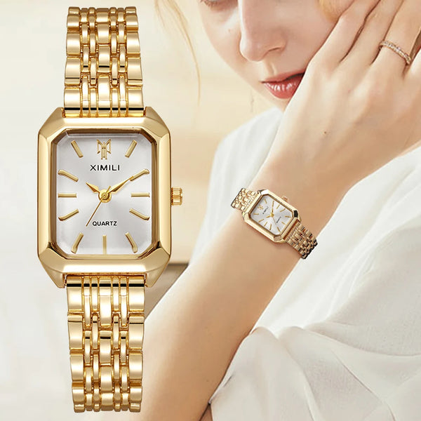 A close-up of a gold-toned quartz wristwatch with a square face and metal bracelet worn on a woman's wrist.