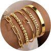 Stack of four chunky gold plated bangles including a chain bracelet and several cuff bangles