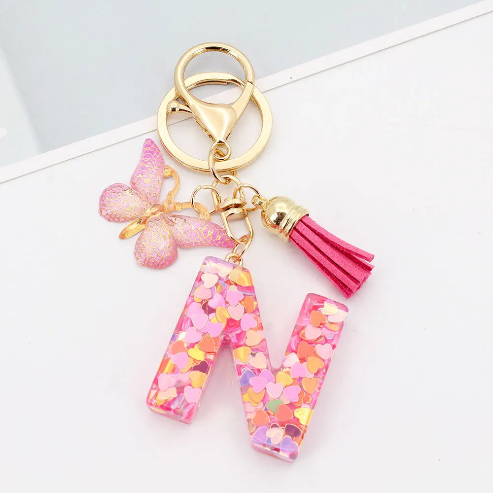 Alphabet letter V acrylic keychain with pink butterfly charm and gold tassel