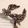 A leopard print retro bow hairband tied around a wooden comb.