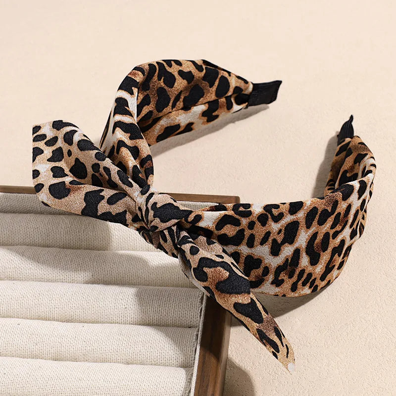A leopard print retro bow hairband tied around a wooden comb.