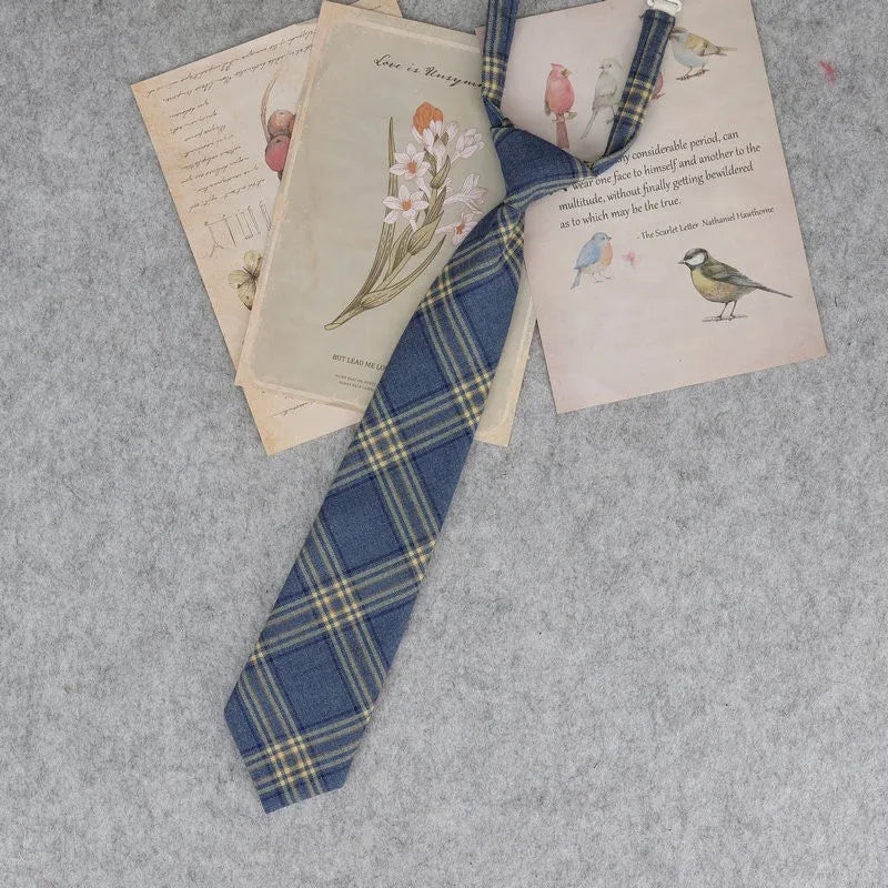 A blue and yellow plaid necktie is displayed alongside vintage-style letters and illustrations on a gray background.