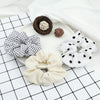 A flat lay showing three knitted hair scrunchie headbands in natural brown, white, and cream colors on a white surface.