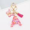 Gold alphabet letter acrylic keychain shaped like the letter A with a pink butterfly and tassel