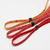 Three strands of adjustable eyewear lanyards or necklaces in shades of orange, red, and gold.