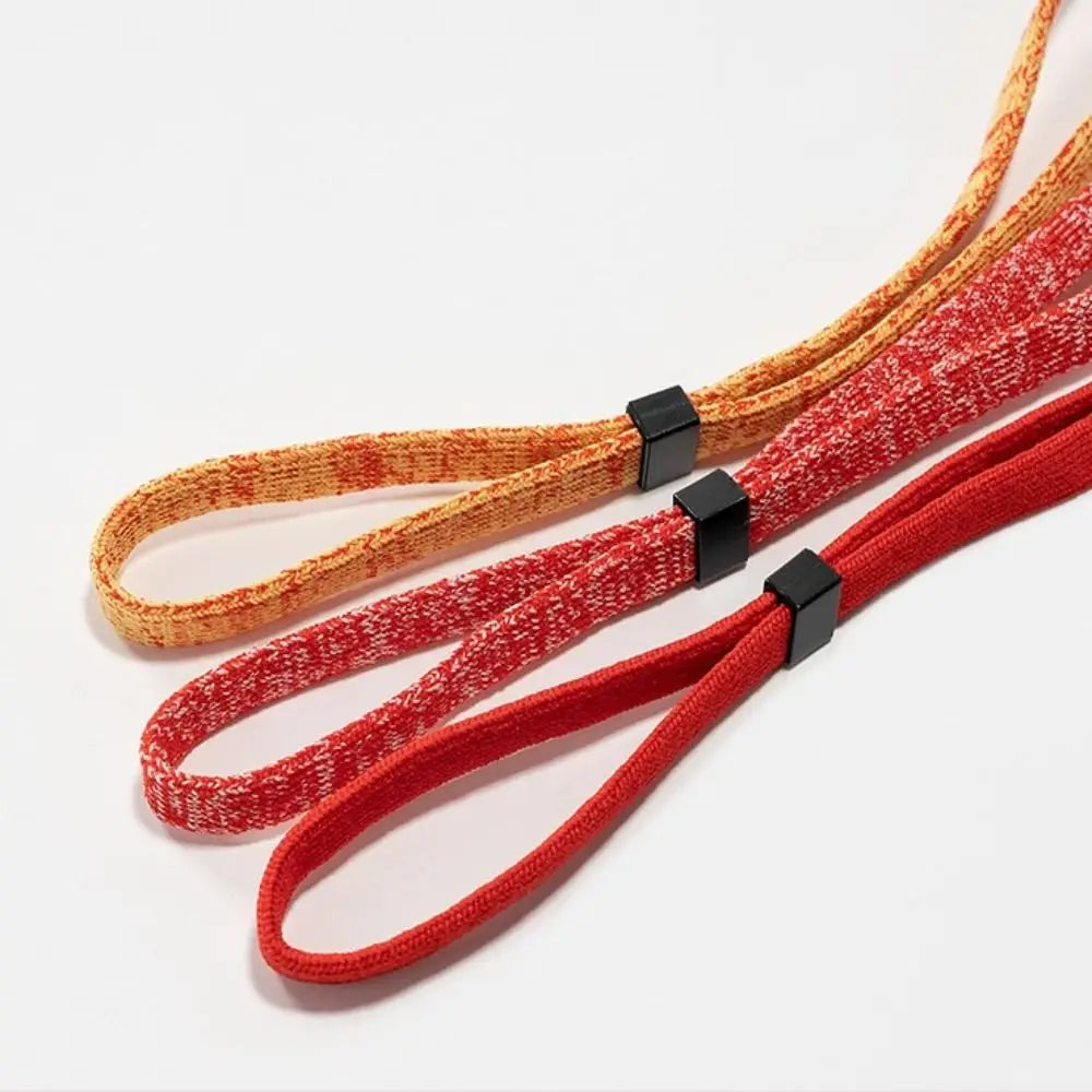 Three strands of adjustable eyewear lanyards or necklaces in shades of orange, red, and gold.