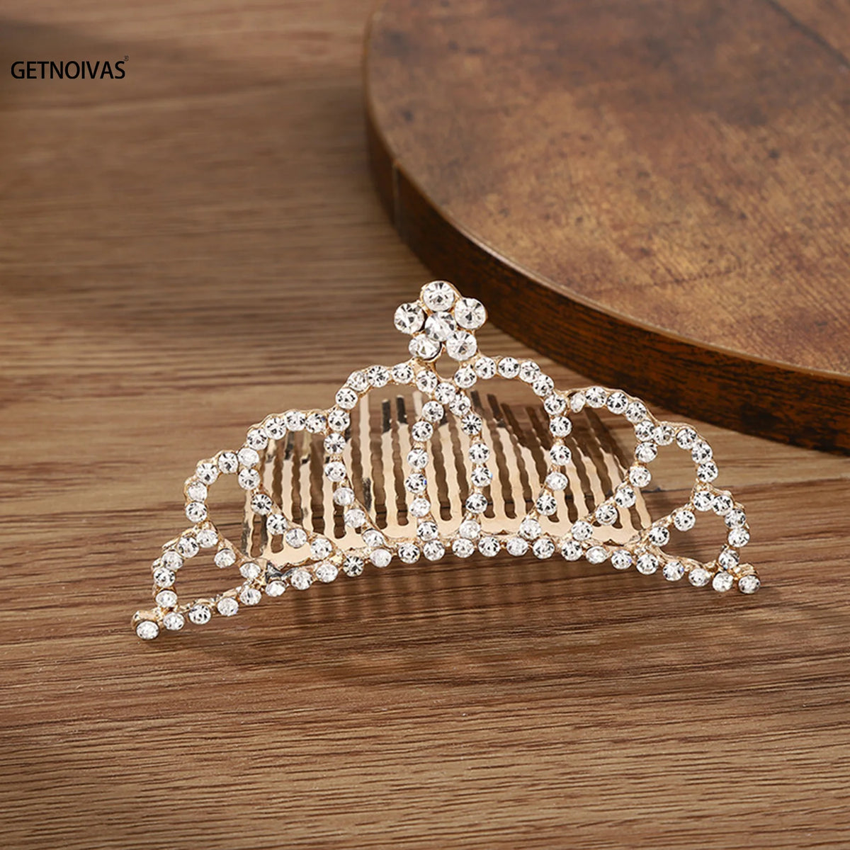 A sparkling crystal princess tiara hair comb for women displayed on a wooden surface.