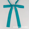A teal fabric ribbon tied in a bow, presented as a classic butterfly ribbon tie set for students.