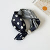 A dark silk scarf with a black and white polka dot pattern tied around a pearl bead.