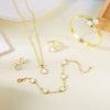 A set of five gold-colored bracelets featuring white enamel plum blossoms displayed on a light background.