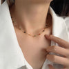 A delicate gold-toned beaded necklace with various colored beads is displayed against a white blazer.