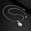Silver chain necklace with a teardrop pendant shaped like the Virgin Mary prayer.