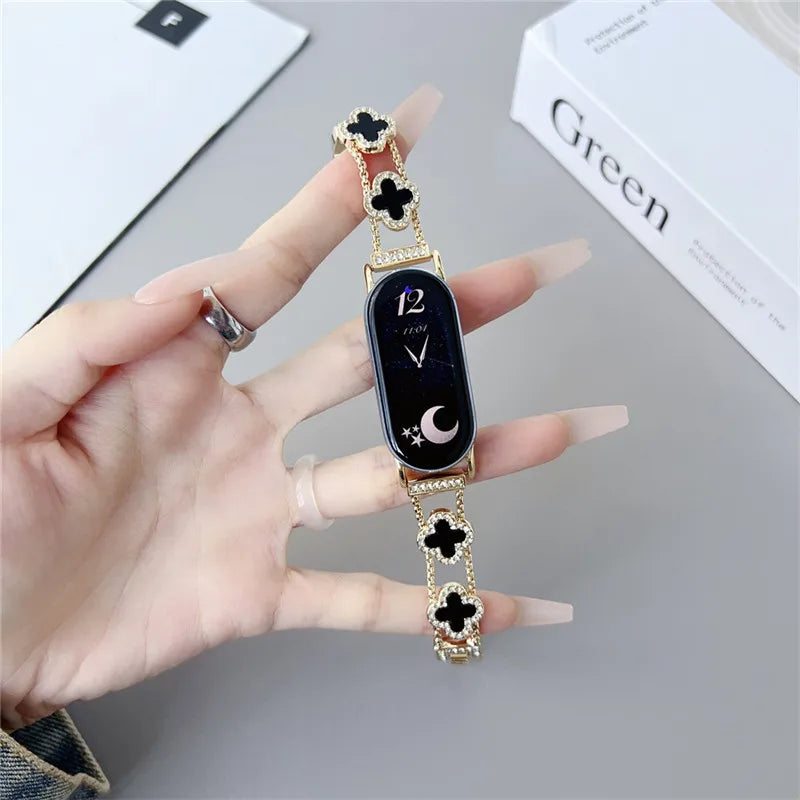 A hand holds a black digital watch with gold accents and four-leaf clover designs on the strap.