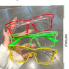 A hand holds a stack of colorful square frame costume glasses in red, green, and yellow.