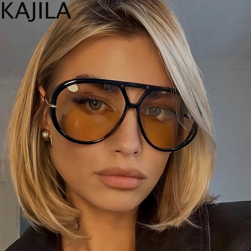 Una mujer modela gafas de piloto vintage sobredimensionadas con lentes tintados en ámbar y montura negra.