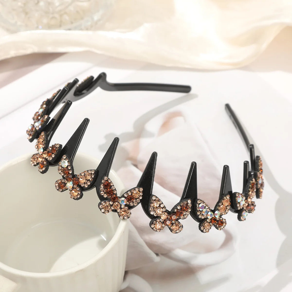 A black hair accessory featuring sparkling rhinestone butterflies arranged in a delicate, curved line.