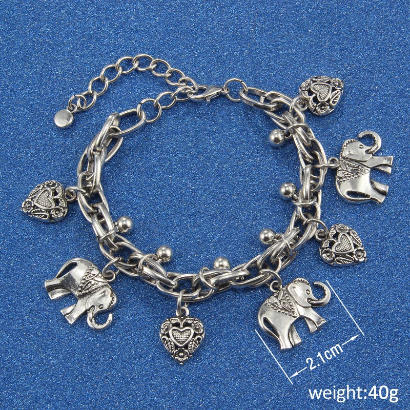 Silver chain bracelet with elephant charms and a heart pendant on a blue background