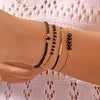 A hand wearing a stack of bohemian pearl beaded bracelets on the wrist.