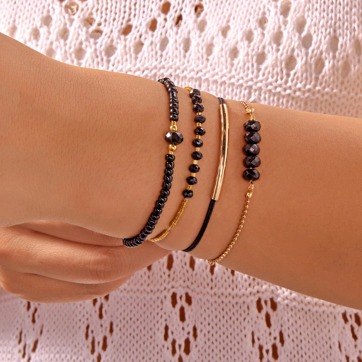 A hand wearing a stack of bohemian pearl beaded bracelets on the wrist.