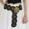 A woman wearing a white skirt and black top features a vintage western denim belt with gold and black embellishments.