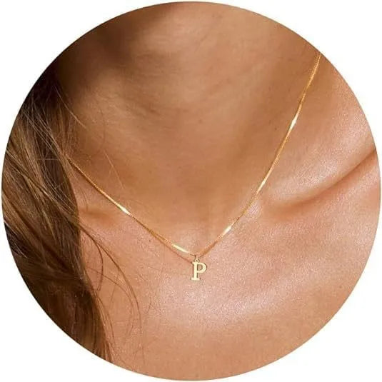 A close-up of a gold plated alphabet initial necklace resting on a person's neck.