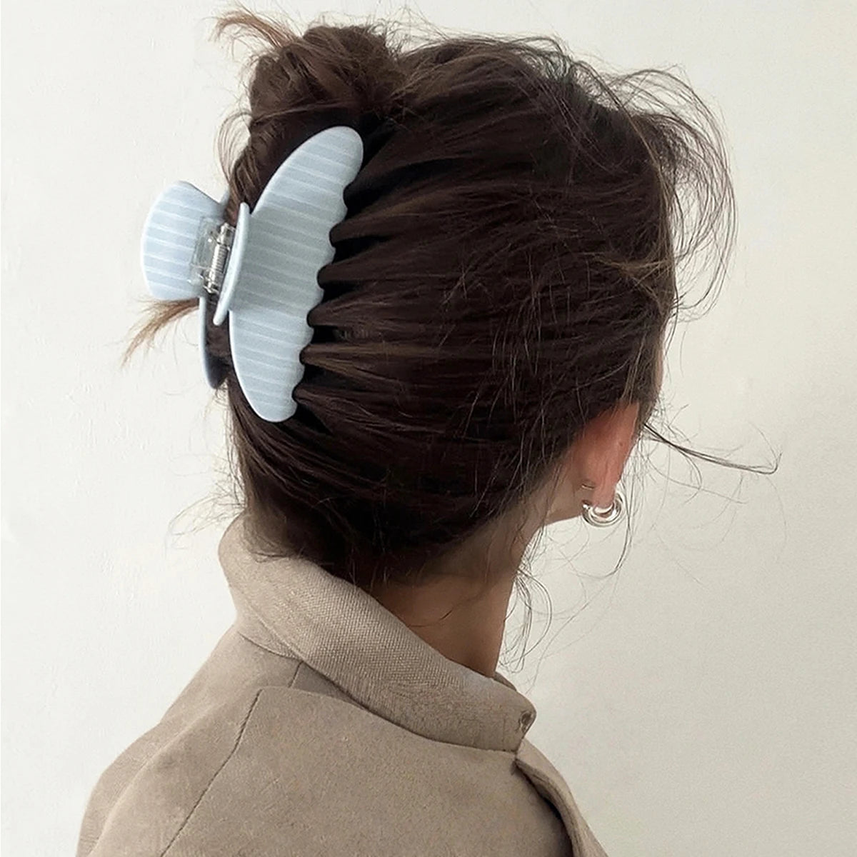 A woman's dark hair is styled with a large, light blue, striped hair clip accessory.