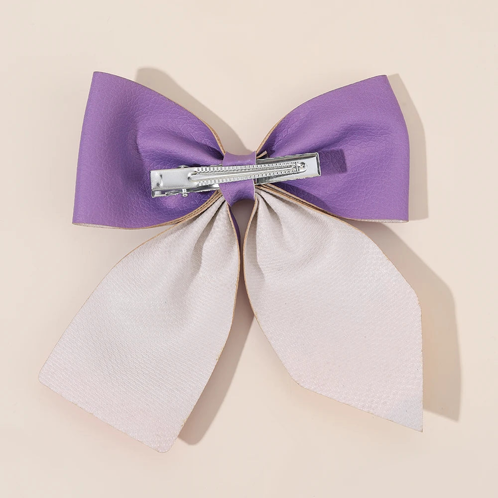A set of purple and light pink fabric bows used as hair clips.