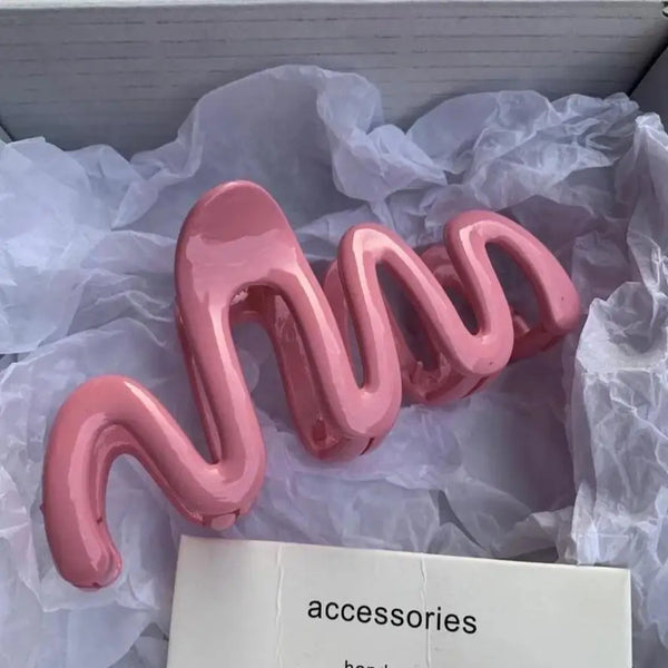 Pink jelly wave hair claw clips resting on white tissue paper.