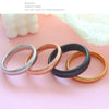 A collection of various gold-toned and silver stainless steel elastic bangle bracelets arranged on a pink surface.