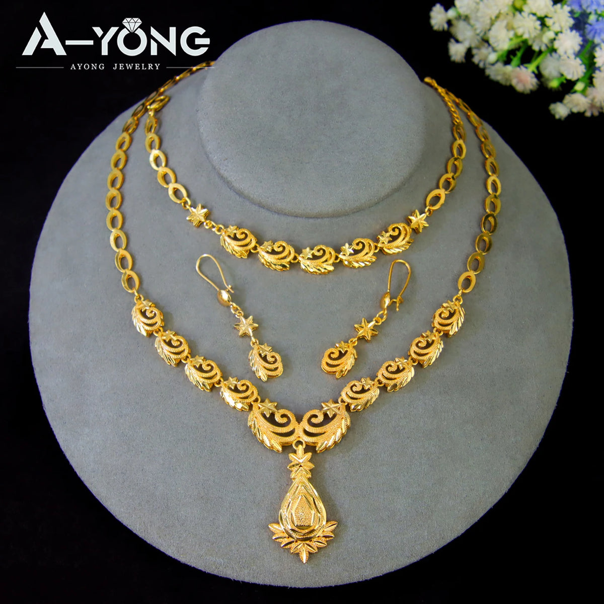 A set of luxury gold plated bridal jewelry featuring layered necklaces and a pendant displayed on a gray stand.
