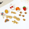 A collection of cute animal and plant metal pin badges including a bunny, strawberry, sun, rainbow, and various other shapes.