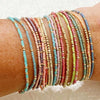 A stack of colorful beaded bangles worn on a wrist.