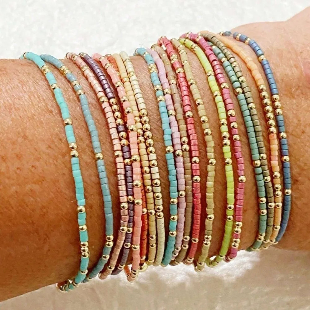 A stack of colorful beaded bangles worn on a wrist.