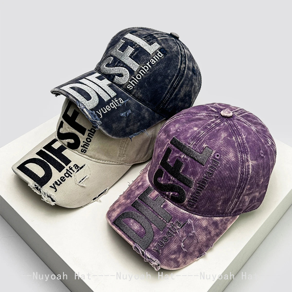 A purple embroidered letter baseball cap shown in a casual studio setting.