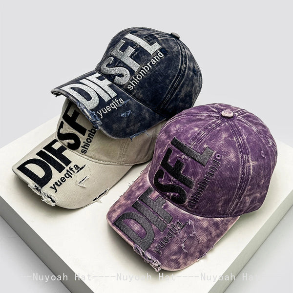 A purple embroidered letter baseball cap shown in a casual studio setting.