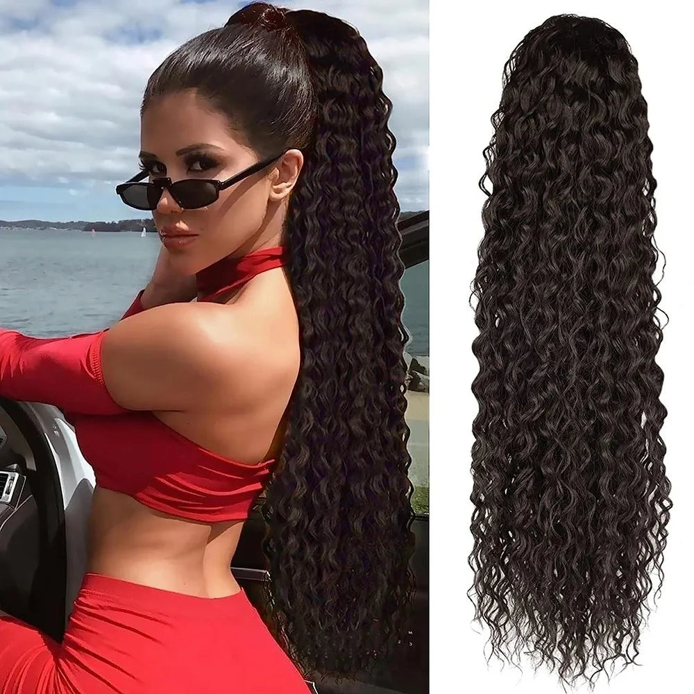 A woman with long black curly hair extensions in a ponytail wearing a red top and pants.
