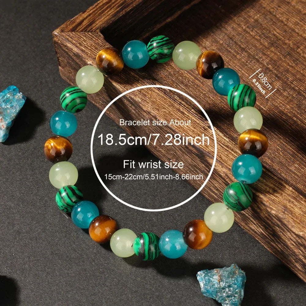 A bracelet made of natural stone beads in shades of green, blue, and amber is displayed on a wooden surface.