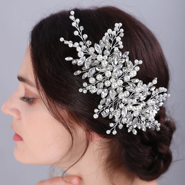 A close-up profile of a woman wearing a bridal headpiece made of sparkling pearl and rhinestone flowers.
