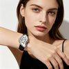 A close-up of a woman wearing a silver and black vintage irregular quartz watch on her wrist.