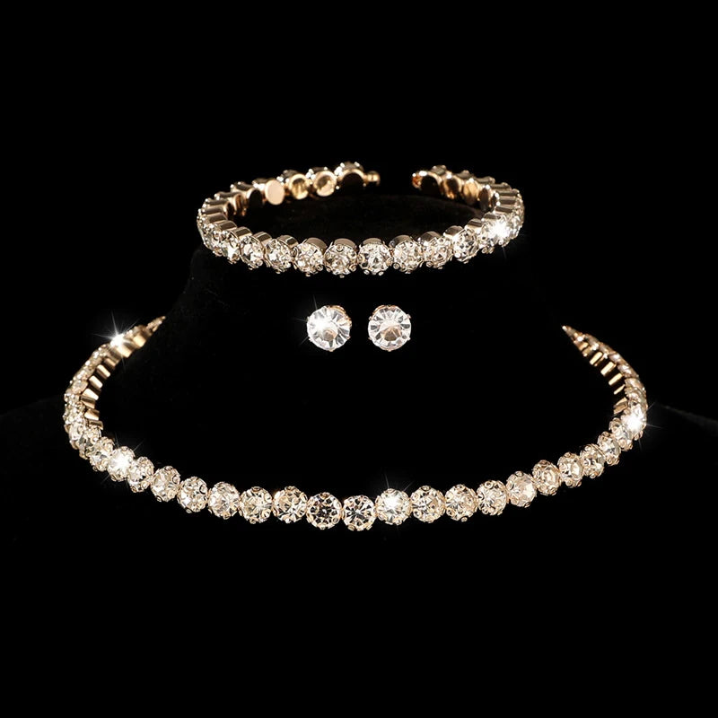 A set of four pieces of crystal jewelry including a bracelet, ring, earrings, and necklace displayed on a black background.