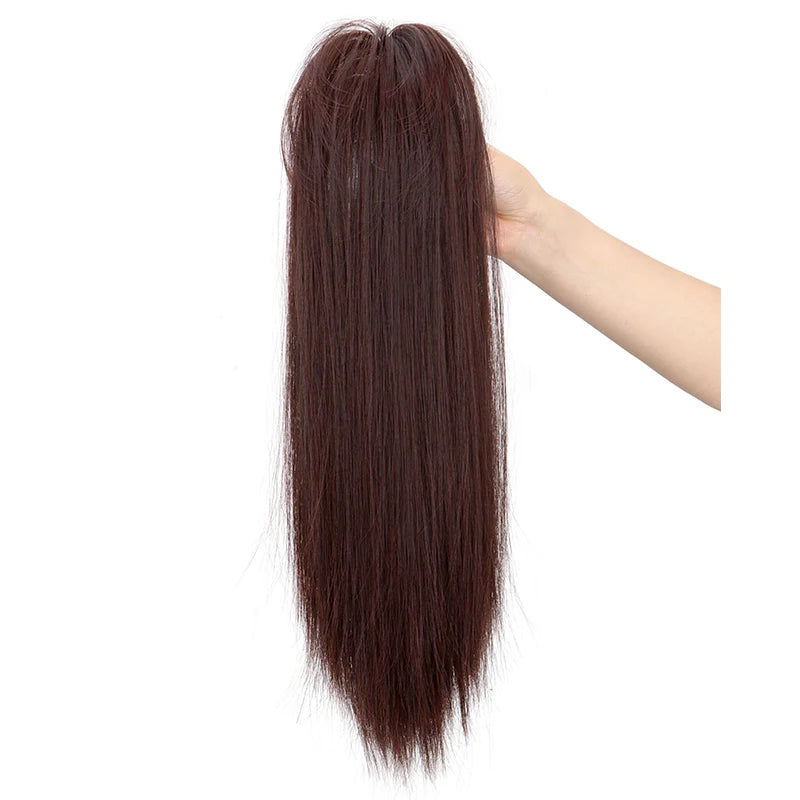 A hand is holding a long, dark brown synthetic straight hair extension with a claw clip.