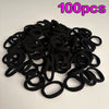 A pile of 100 black seamless elastic hair ties for ponytail holders.