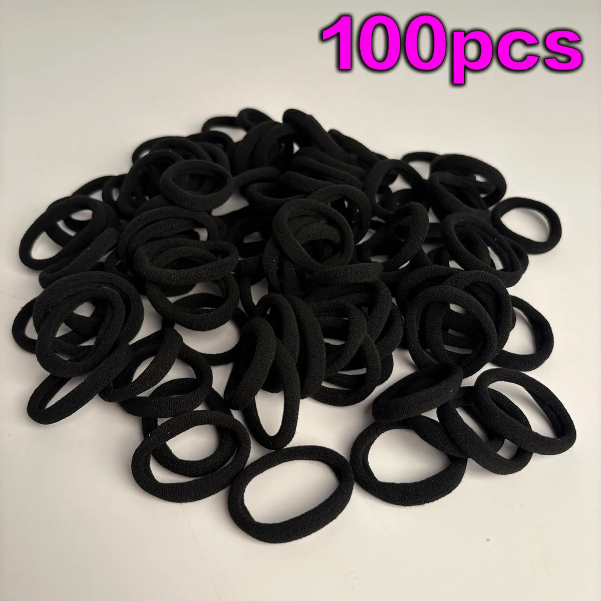 A pile of 100 black seamless elastic hair ties for ponytail holders.