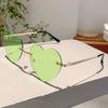 Vintage Herzform-Sonnenbrille ohne Rand mit grün getönten Linsen und goldenen Akzenten auf weißem Untergrund.